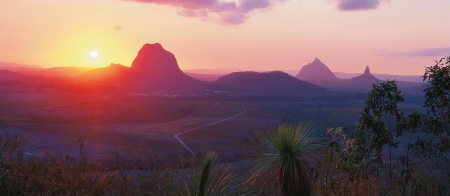 a sunset over a body of water with a mountain in the background