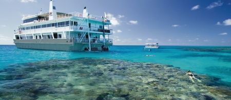 a blue and white boat sitting next to a body of water